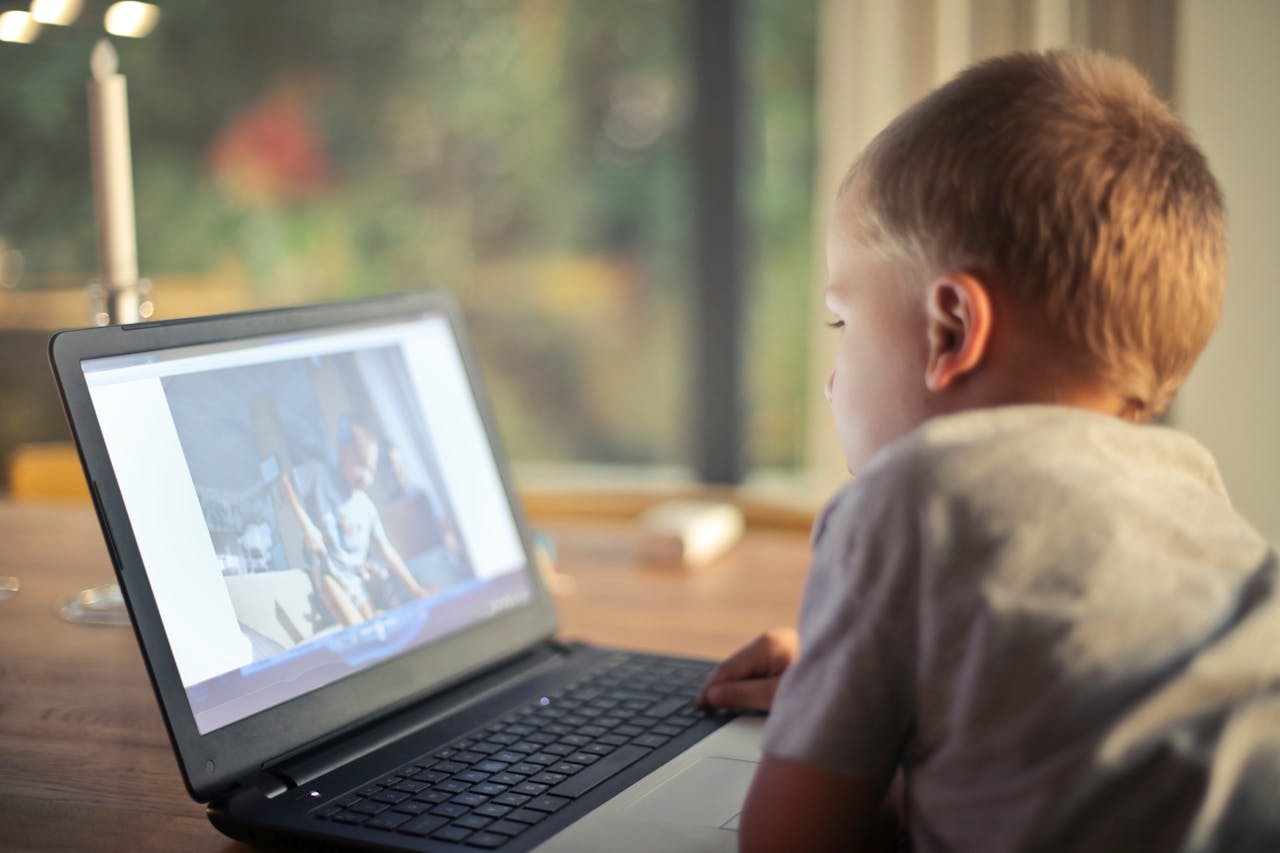 Home A young boy engrossed in watching content on a laptop in a cozy home setting.